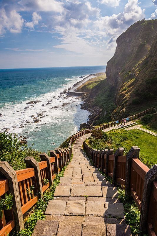 a stone path leading to the ocean on a sunny day