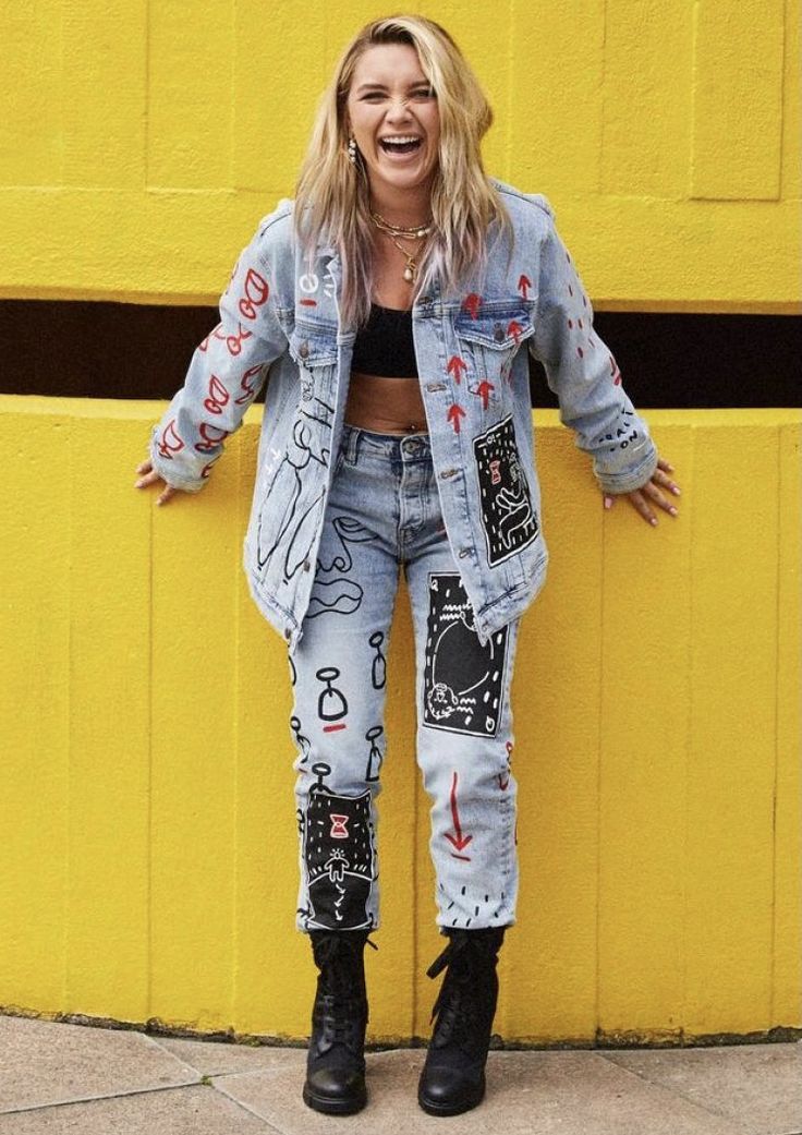 a woman standing in front of a yellow wall with her hands on her hips and smiling