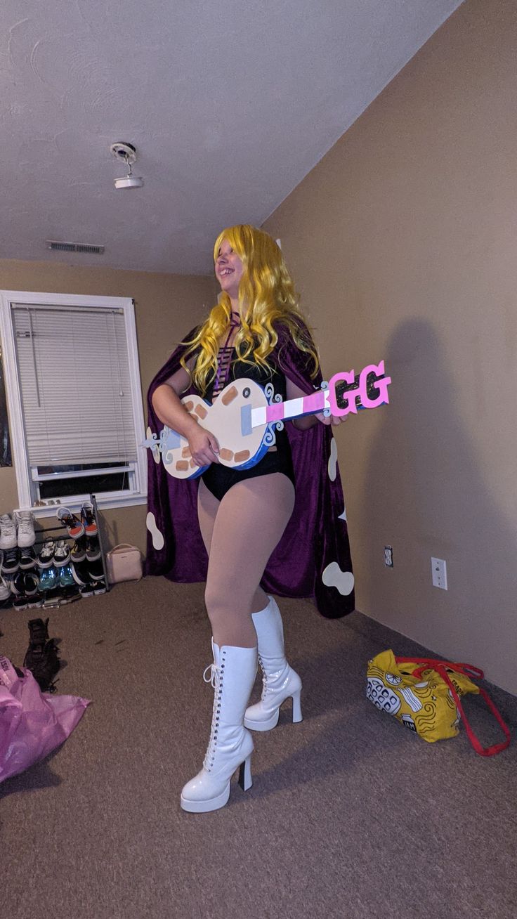 a woman dressed in costume holding a guitar and posing for the camera while wearing high heeled boots