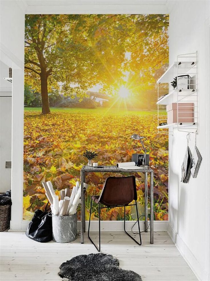 a room with a desk, chair and wall mural in the shape of an autumn tree