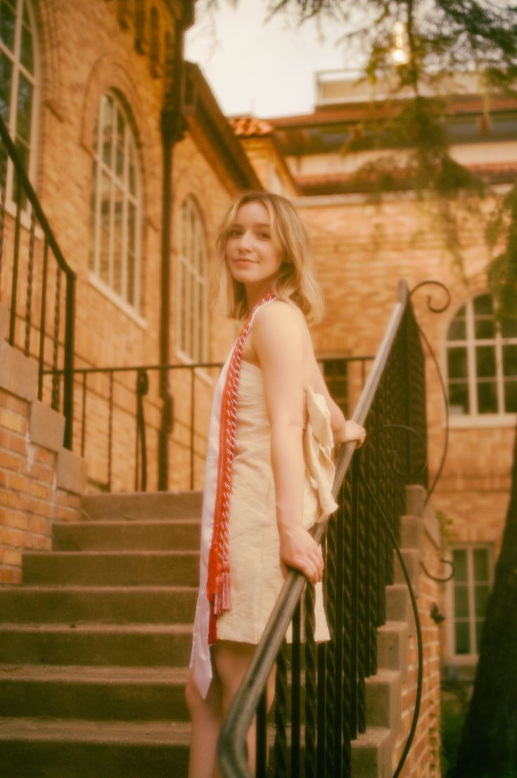 a woman standing on the stairs in front of a brick building with an iron hand rail