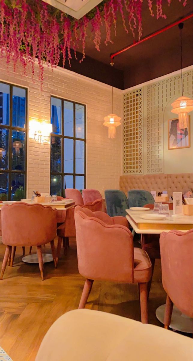 the interior of a restaurant with pink chairs and chandeliers hanging from the ceiling