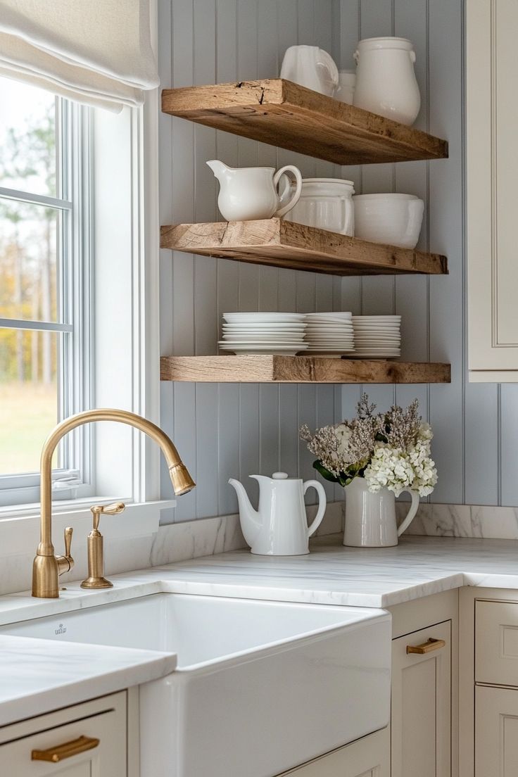 a kitchen with white cabinets and open shelving above the sink, filled with dishes