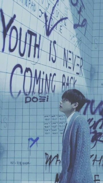 a young man standing in front of a wall with writing on it that says youth is never coming back