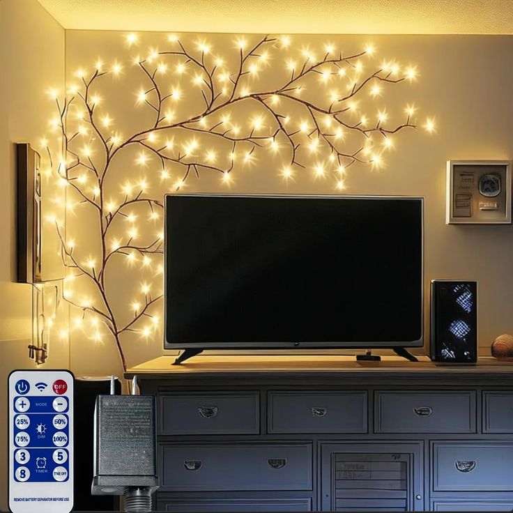 a flat screen tv sitting on top of a wooden dresser next to a wall covered in lights