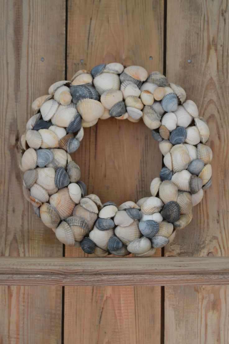 a wreath made out of seashells sitting on top of a wooden wall