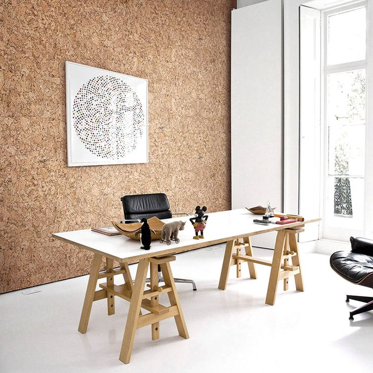 an office with corked walls and leather chairs in front of the desk is shown