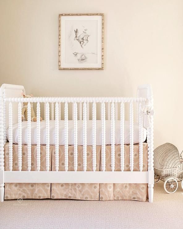 a white crib in a baby's room next to a painting on the wall