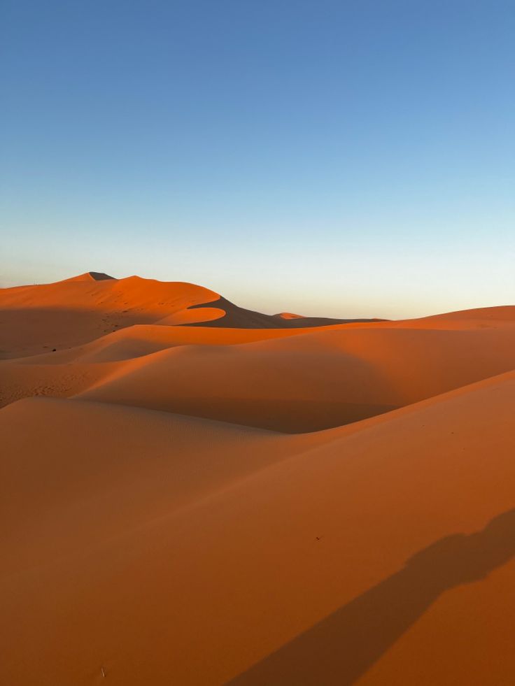 the sun is setting over sand dunes in the desert