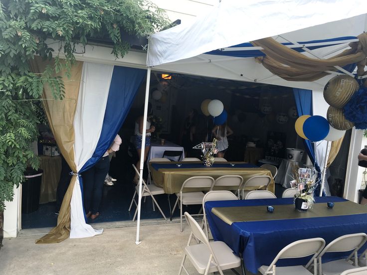 an outdoor event with blue and white tables set up in front of a large tent