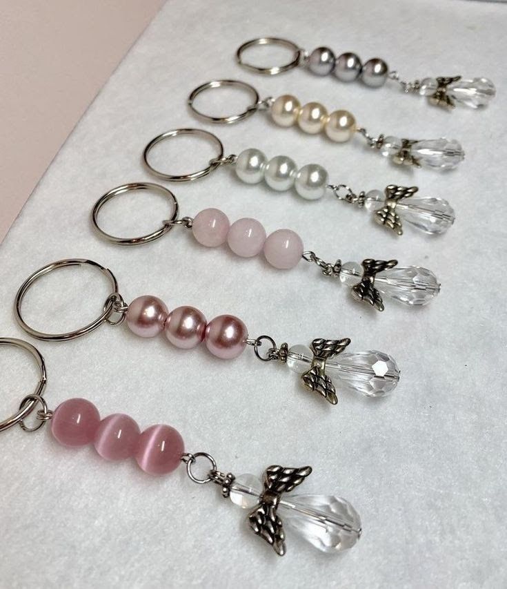 six pairs of key chains with beads and charms on them sitting on a white surface