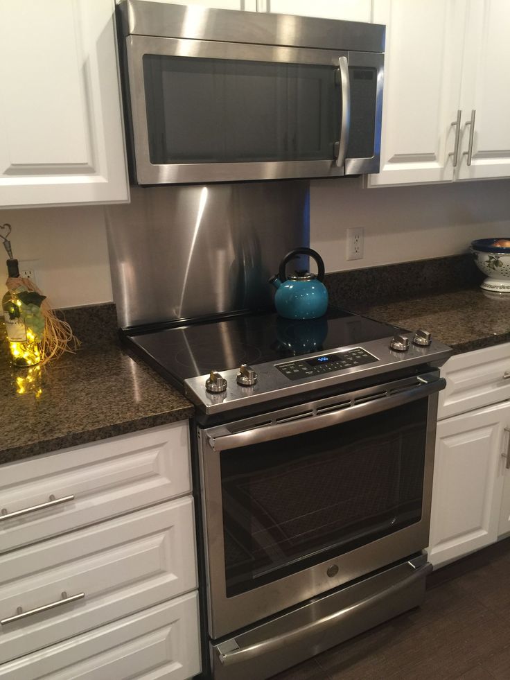 a stainless steel stove top oven sitting in a kitchen next to white cabinets and drawers