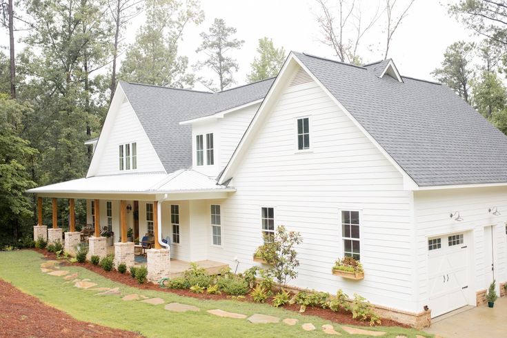 a large white house with lots of windows on it's roof and front porch