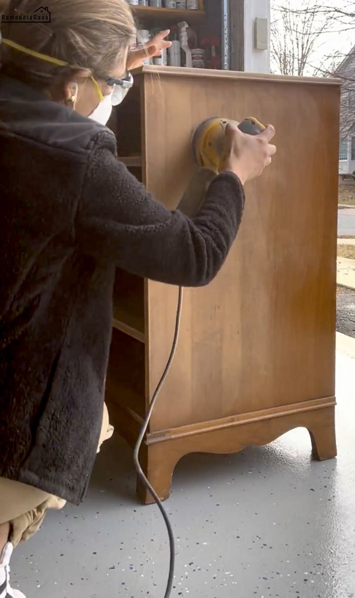 a woman using a power drill on a wooden cabinet