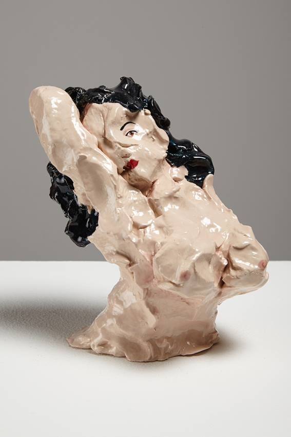 a ceramic sculpture of a woman with her arms behind her head, sitting on a white surface