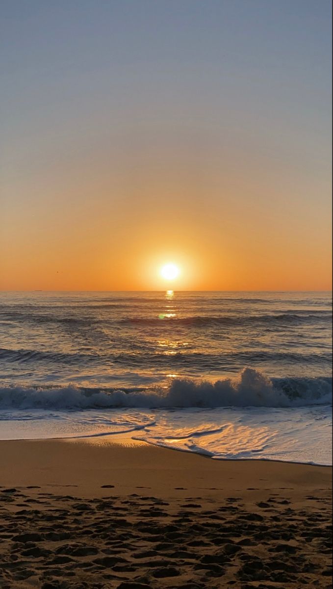 the sun is setting over the ocean with waves