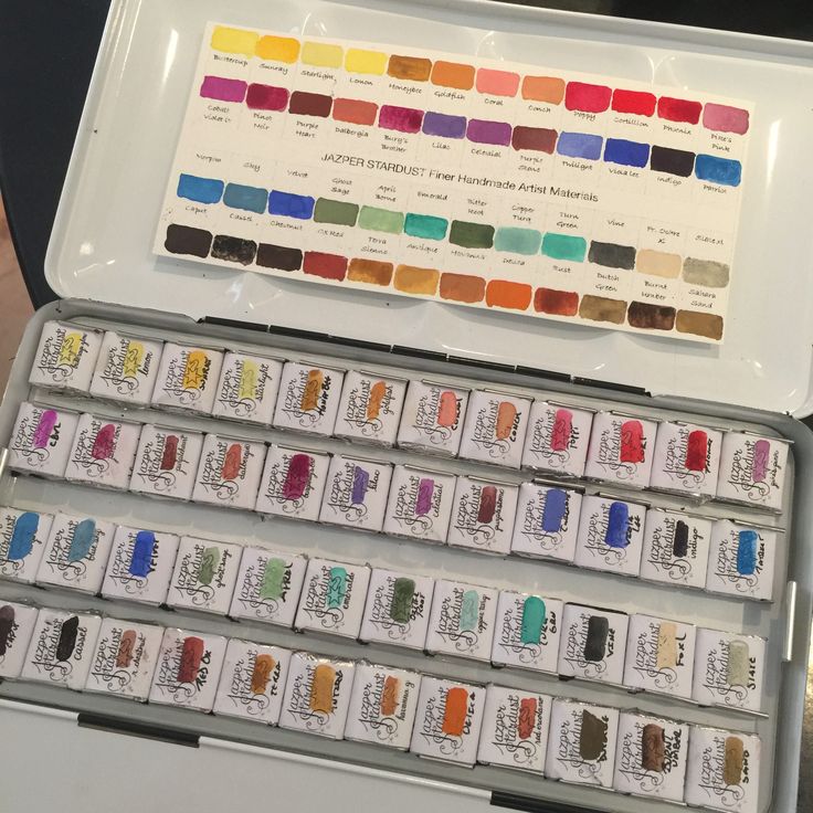 an open box with several different colors of watercolors in it and the lid opened