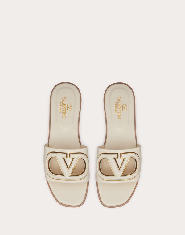 Valentino Garavani VLogo cut-out slide sandal in calfskin leather - VLogo Signature cut-out calfskin detail with mirror-effect trim - Insole with padded heel for extra comfort - Heel height: 5 mm / 0.2 in. - Made in Italy Luxury Slides With Branded Insole And Open Heel, White Luxury Calf Leather Mules, Luxury White Calf Leather Mules, Luxury Beige Slip-on Sandals, Elegant Flat Calf Leather Slides, Luxury Flat Mules With Leather Lining, Calf Leather Open Toe Slides, Elegant Beige Leather Slides, Luxury Cream Mules