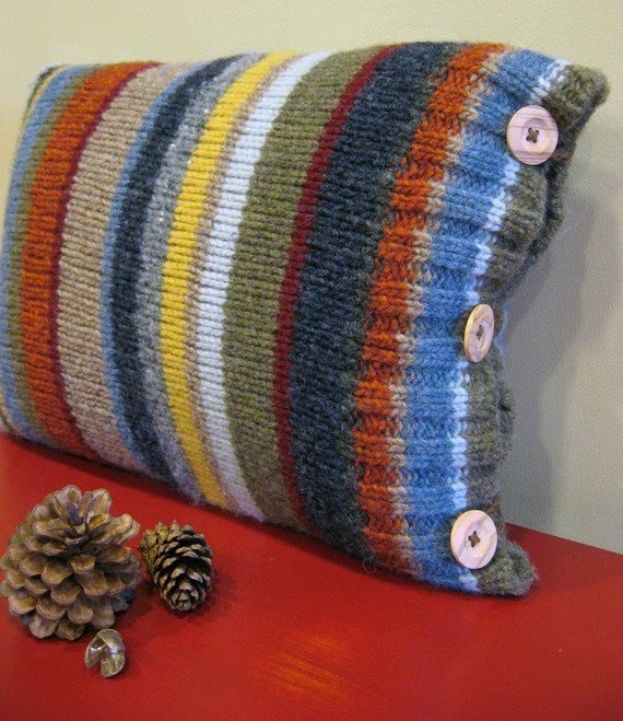 a pillow with buttons on it sitting on top of a red table next to pine cones