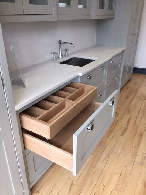 an open drawer in a kitchen next to a sink and counter top with drawers on both sides