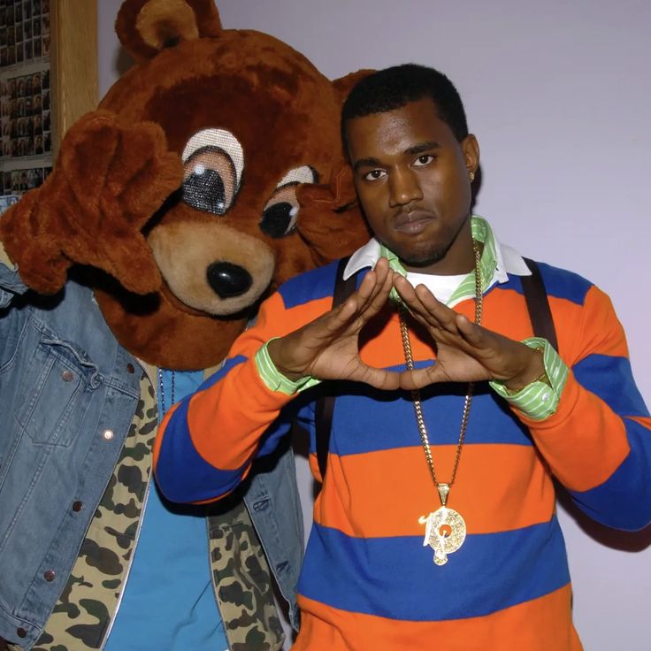 a man standing next to a large stuffed animal wearing an orange and blue striped shirt