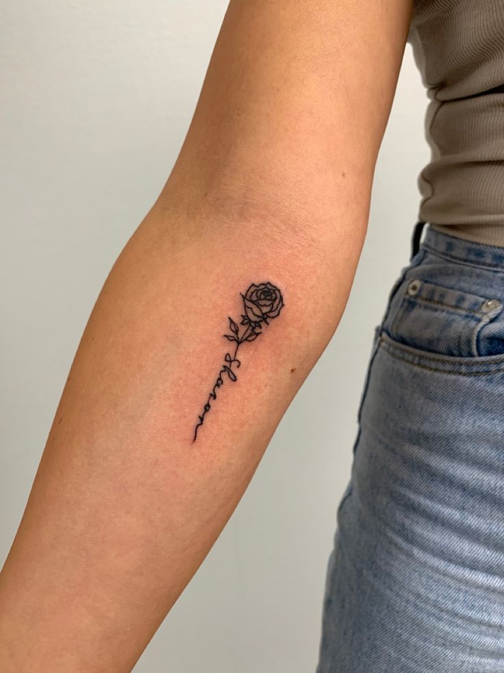 a woman's arm with a rose tattoo on the left side of her arm