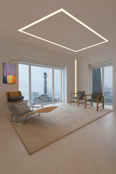 a living room filled with furniture and large windows overlooking the cityscape in the distance