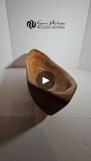 a wooden bowl sitting on top of a white table next to a logo for wood carving