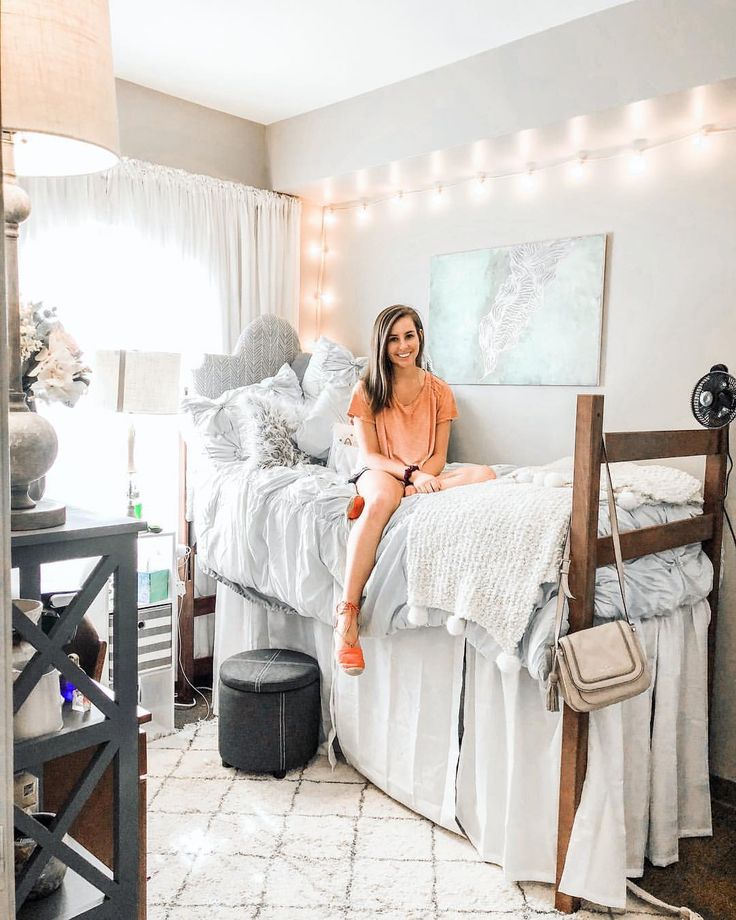 a woman sitting on top of a bed in a room with white sheets and pillows