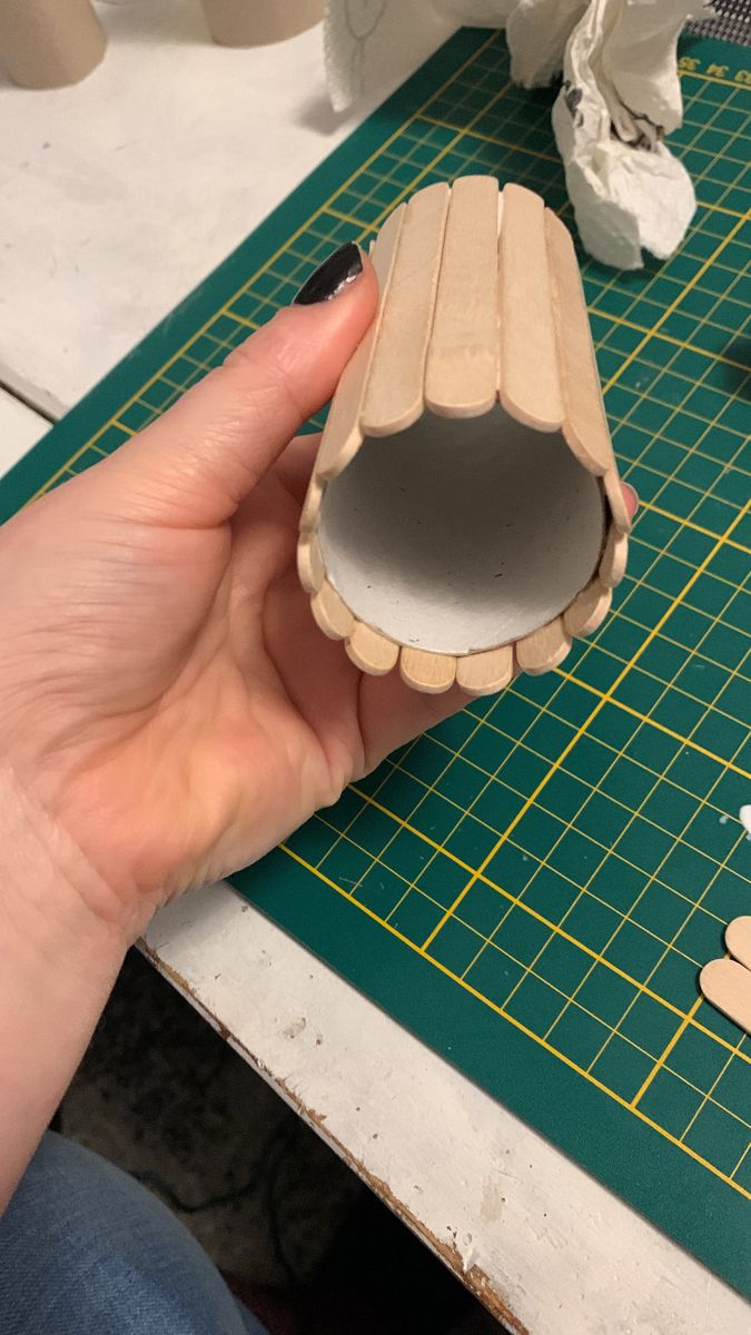 a person holding a piece of wood on top of a green cutting board with scissors