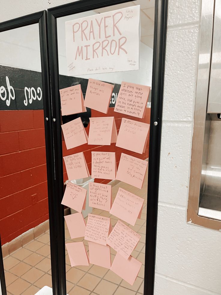 a bulletin board with notes attached to it in front of a door that says prayer mirror