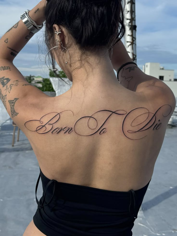 a woman with tattoos on her back and the words born to die written in cursive font