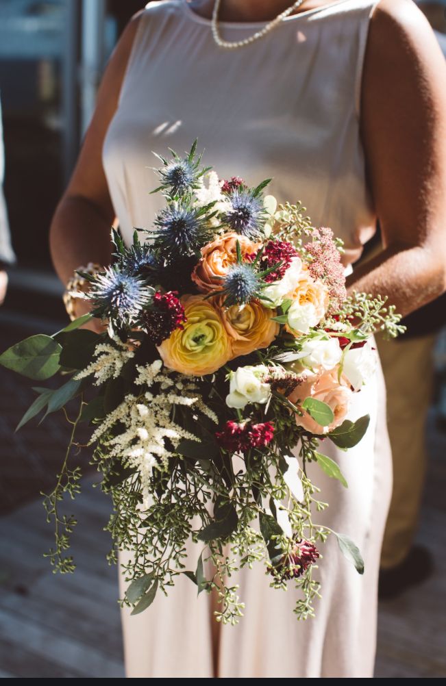 a woman holding a bouquet of flowers in her hand and wearing a white dress on the other side