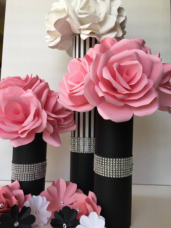 some black and white vases with pink flowers in them