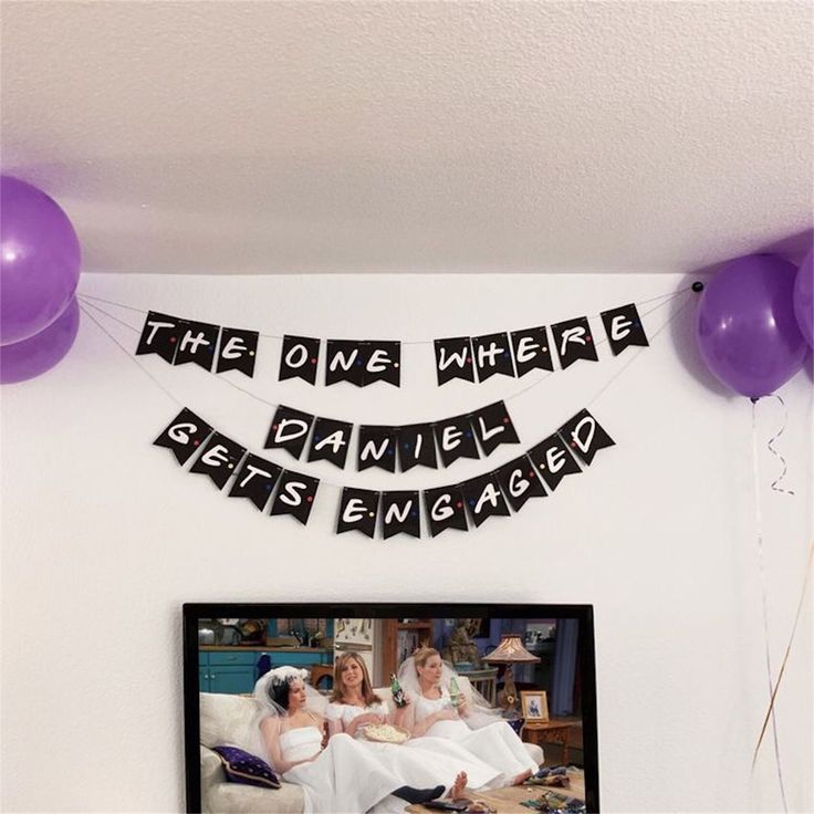 a tv sitting on top of a table next to balloons and a sign that says the one where she gets married