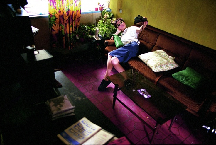 two people sitting on a couch in a room with yellow walls and purple flooring