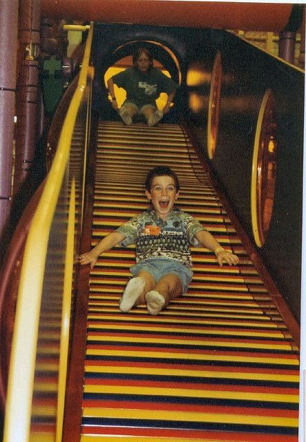 a young boy is sliding down an indoor roller coaster