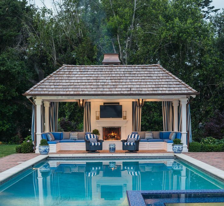 an outdoor living area next to a swimming pool with lounge chairs and a fire place