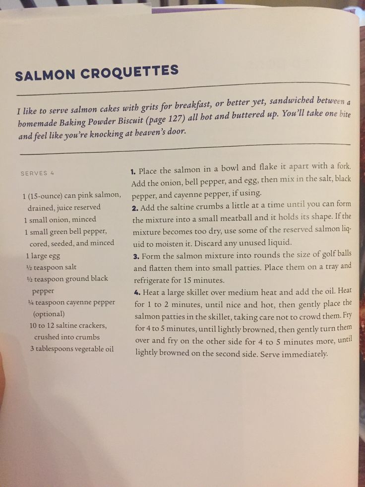 someone is holding up a recipe book for salmon croquettes