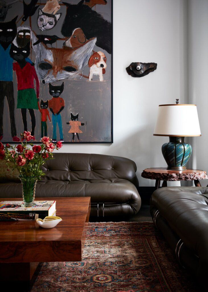 a living room filled with furniture and a large painting on the wall above it's coffee table