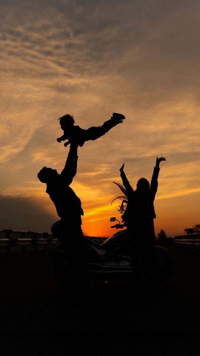 two people riding on the back of a motorcycle with their arms up in the air