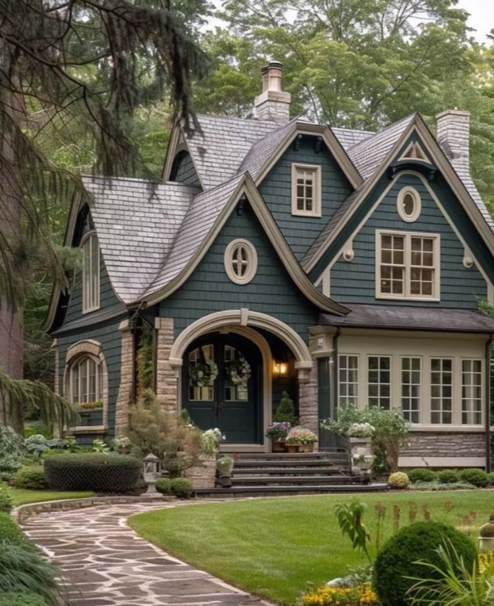 a blue house with lots of windows in the front yard and landscaping on both sides