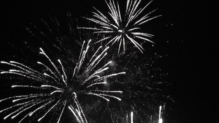 fireworks are lit up in the night sky with black and white image behind them,