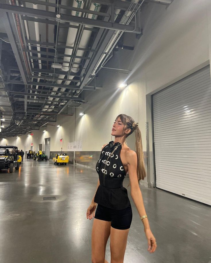 a woman standing in an empty garage with her eyes closed and one hand on her hip