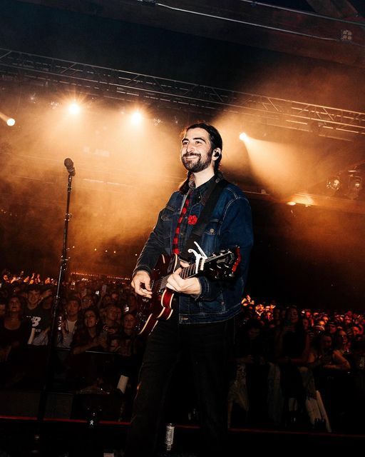 a man standing in front of a microphone while holding a guitar