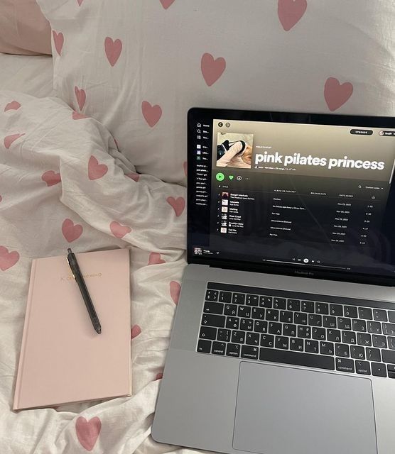 an open laptop computer sitting on top of a bed next to a notepad and pen