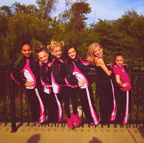 a group of young women standing next to each other on top of a metal fence