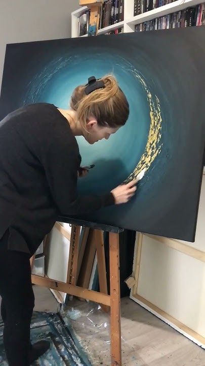 a woman is painting on an easel in her studio