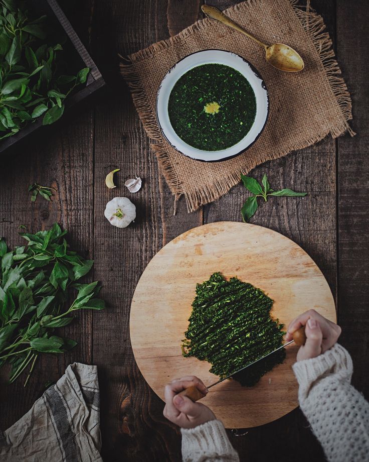 a person cutting up food on top of a wooden table next to other foods and vegetables