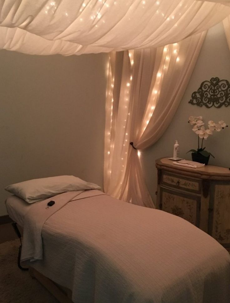 a white bed sitting under a canopy covered in lights